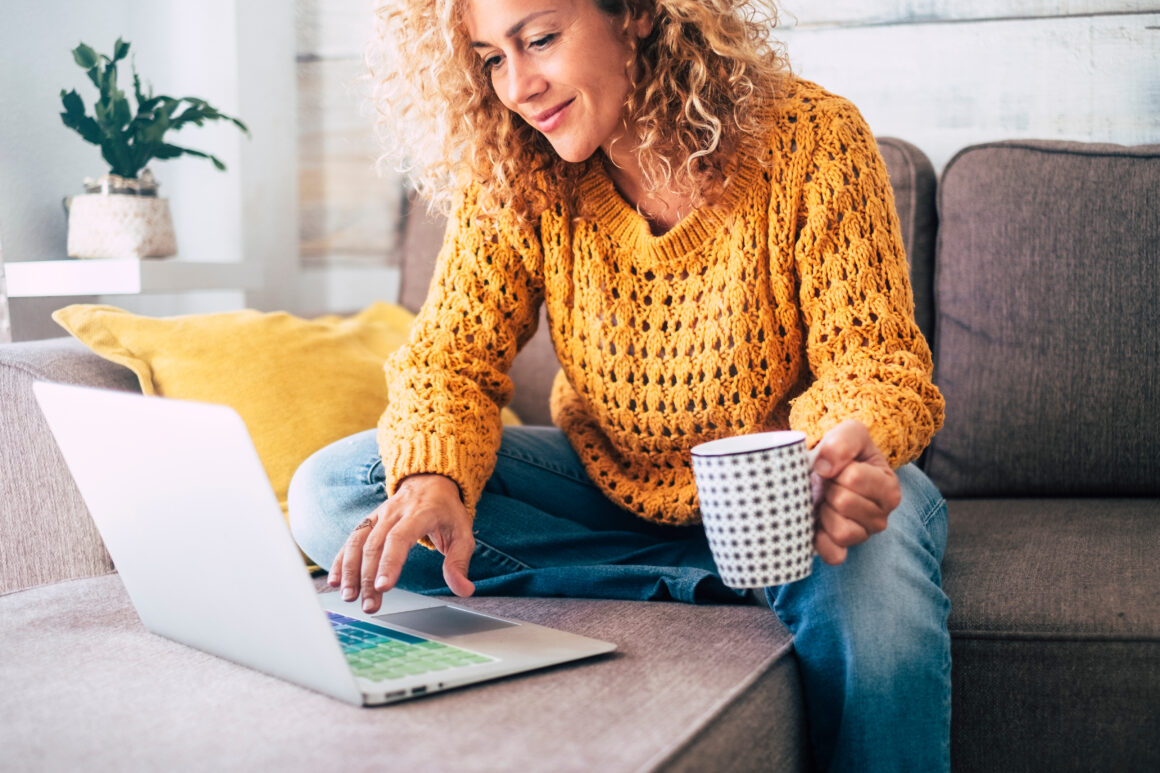 Woman sitting on her sofa with her laptop looking at 100% Mortgage offers.